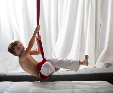 ni&ntilde;o colgado de columpio de yoga con gesto sonriente