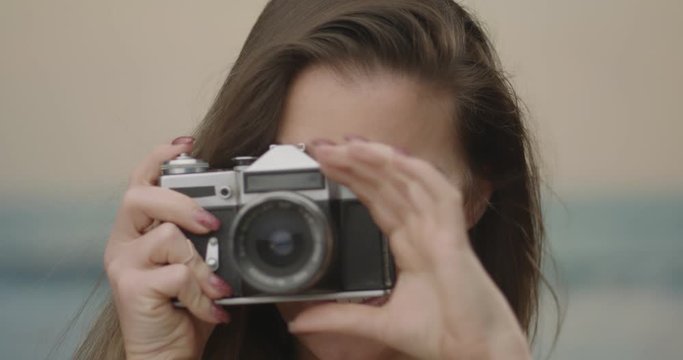 Portrait of a young woman with analog photo camera taking a picture	