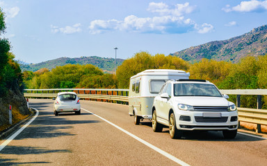 Fototapeta premium Camper and cars on road at at Mediterranean Sea in Sardinia Island, Italy summer. Caravan motorhome on holidays at highway. Minivan rv on motorway. Mixed media.