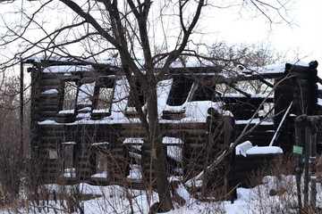 Snow, a destroyed wooden house after a fire.