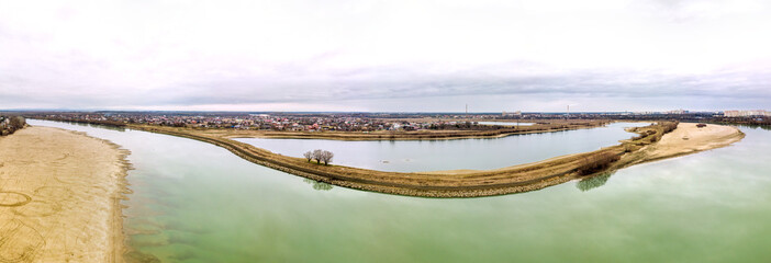 Starobrzegokai Lake beyond the Kuban River and Adyghe aul on a cloudy January day - aerial drone panorama.