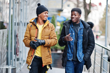 Two african male friends talking together, wear on jackets at cold weather.