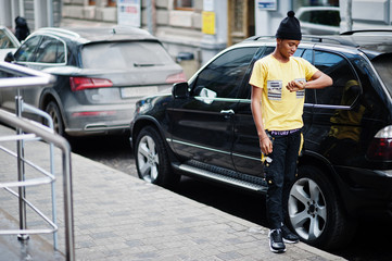 African man wear on black hat posed outdoor against business car.