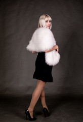 Portrait of a woman with blond hair, wearing a tight dress. On the shoulders of a fur Cape.