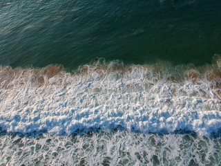 Obraz na płótnie Canvas aerial view from a big wave crashing in a beach. Drone view