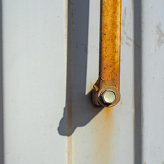 Corrugated metal fence with rusty strip and bolts is close
