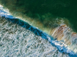Fototapeta na wymiar aerial view from a big wave crashing in a beach. Drone view