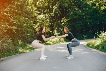 Beautiful sportsgirls in a summer forest. Ladies in a black top