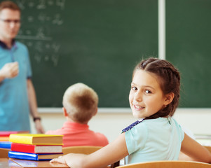 Young male teacher explaining math at the blackboard during a lesson at school