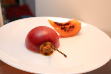 Ripe tamarillo in a section. Tamarillo on a white plate.