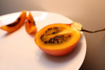 Ripe tamarillo in a section. Tamarillo on a white plate.