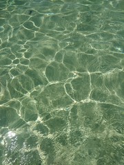 close up of clear sea and sunlight reflecting off sandy sea bed