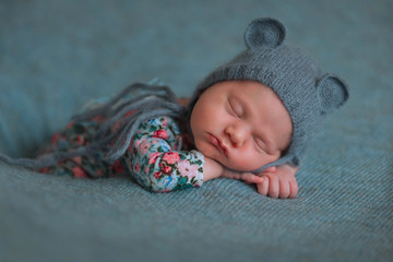 Beautiful little newborn baby in a mouse cap sleeps sweetly on a blue background.