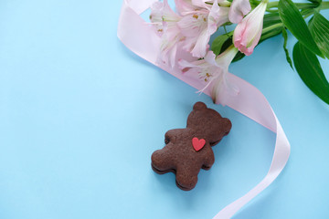 Cookies in the shape of a bear with a pink ribbon on a pink background.