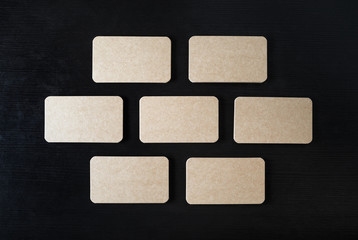 Blank kraft business cards mock-up on black wood table background. Copy space for text. Flat lay.