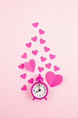 Paper hearts and alarm clock over the pink pastel background. Love, Sainte Valentine, mother's day, birthday greeting cards, invitation, celebration concept