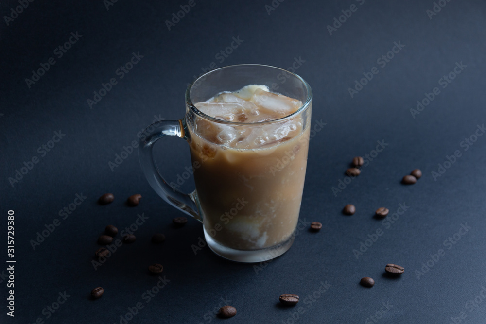 Wall mural glass cup of ice coffee and milk on black background with coffee beans