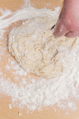 Kneading dough with flour on a wooden table at home