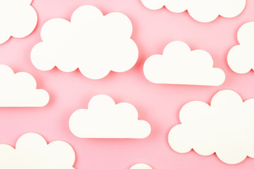 White paper cut out clouds over pink background.