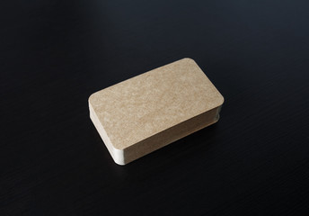 Photo of kraft business cards stack on black wooden background. Blank template for branding identity.