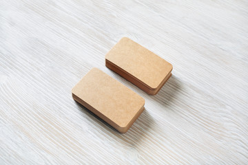 Two piles of blank kraft business cards on light wooden background. Branding mock up.