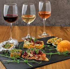 Glasses of red, pink and white wine with various types of cold snacks. Food and drink concept.