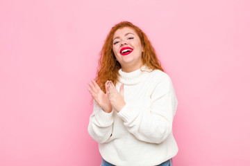 young red head woman feeling happy and successful, smiling and clapping hands, saying...