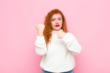 young red head woman looking impatient and angry, pointing at watch, asking for punctuality, wants...