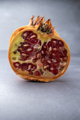 View of pomegranate cut in half with its red nuggets, on gray background in vertical, with copy space