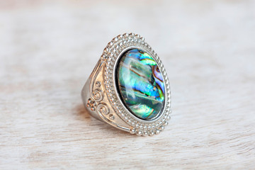 Blue and green mother pearl silver plated ring on white wooden background