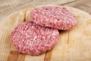 Soft focus. Two raw pink beef cutlets on a cutting board.