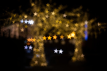Blurred Chrismas and New Year illumination on the street. Trees with bokeh star shape lights. Abstract New Year background.