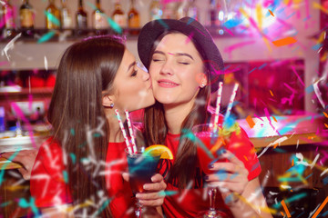 Obraz na płótnie Canvas Confetti party. Two young lesbian girls kissing at a club party.