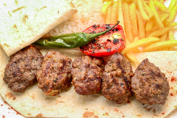 Grilled veal meatballs with potato garnish on wooden background