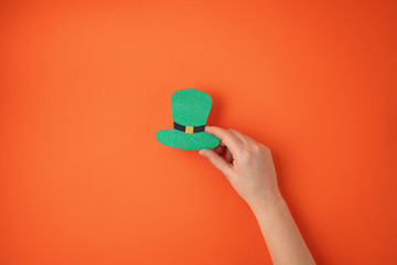 Top view over woman hand holding Saint Patrick day symbols in traditional colors. Greeting card, invitation, celebration idea