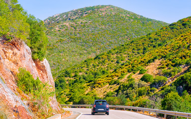 Car on the road at Carbonia in Sardinia Island in Italy summer. Transport driving on the highway of Europe. Holiday View on motorway. Cagliari province. Mountains on background. Mixed media.