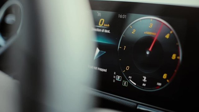 Close up HD footage of the digital display of a modern car, with a revving tachometer. 