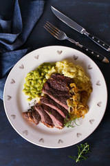 Grilled fillet beef steak with mashed potato, peas and fried onion. View from above, top view