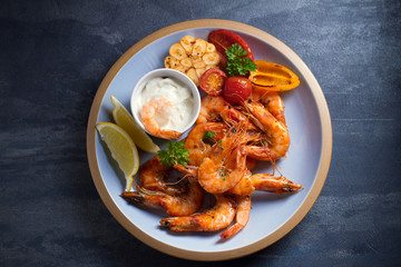 Shrimps or prawns with vegetables, garlic and sauce on plate. Overhead, top view