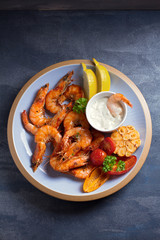 Shrimps or prawns with vegetables, garlic and sauce on plate. Overhead, top view