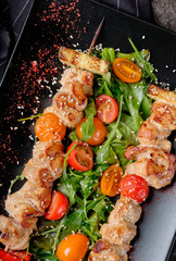 Grilled kebabs with red pepper, tasty spicy, onion and colorful vegetable on black plate, stone background. Top view bbq meat chicken kebab. Close up, selective focus.