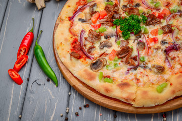 Traditional italian pizza with minced meat on wooden background