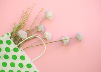 Bunch of flowers in paper bag against pastel pink background