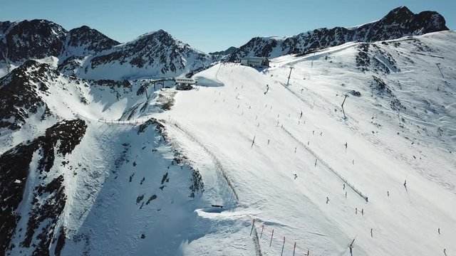 Aerial view smooth movement along the ski slopes in the ski resort of Grandvalira in Andorra. Magnificent snowy mountains and blue sky. Winter landscape