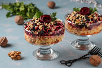 Traditional Russian salad with cheese, beets and carrots, decorated with beet roses, nuts and prunes, portioned serving, Horizontal orientation