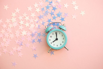 Vintage alarm clock on pink background with star shiny confetti