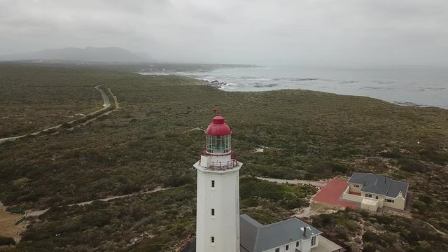 4K summer foggy day aerial drone video of famous Danger Point Lighthouse on southern point of Walker Bay peninsula near Indian Ocean coastal town Gans Bay, Garden Route, Western Cape, South Africa
