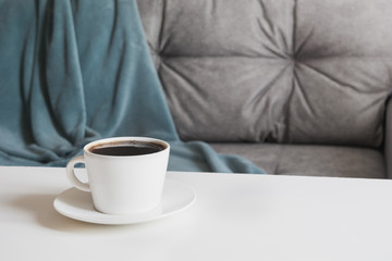 Cup of black coffee in interior for take a break with soft cozy couch. Space for display your products.
