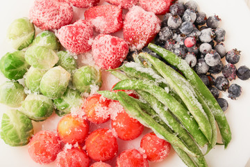 Top view of frozen foods in a plate - strawberries with shadberry and brussels sprouts with...