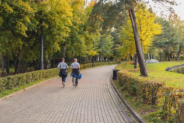 Fototapeta premium Young man and senior man are jogging in the morning autumn park